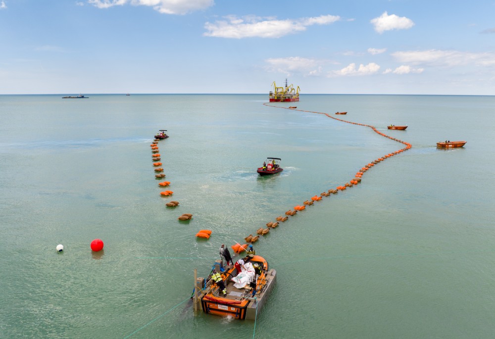 View of fishing boats in the water with a distant offshore platform and floating markers