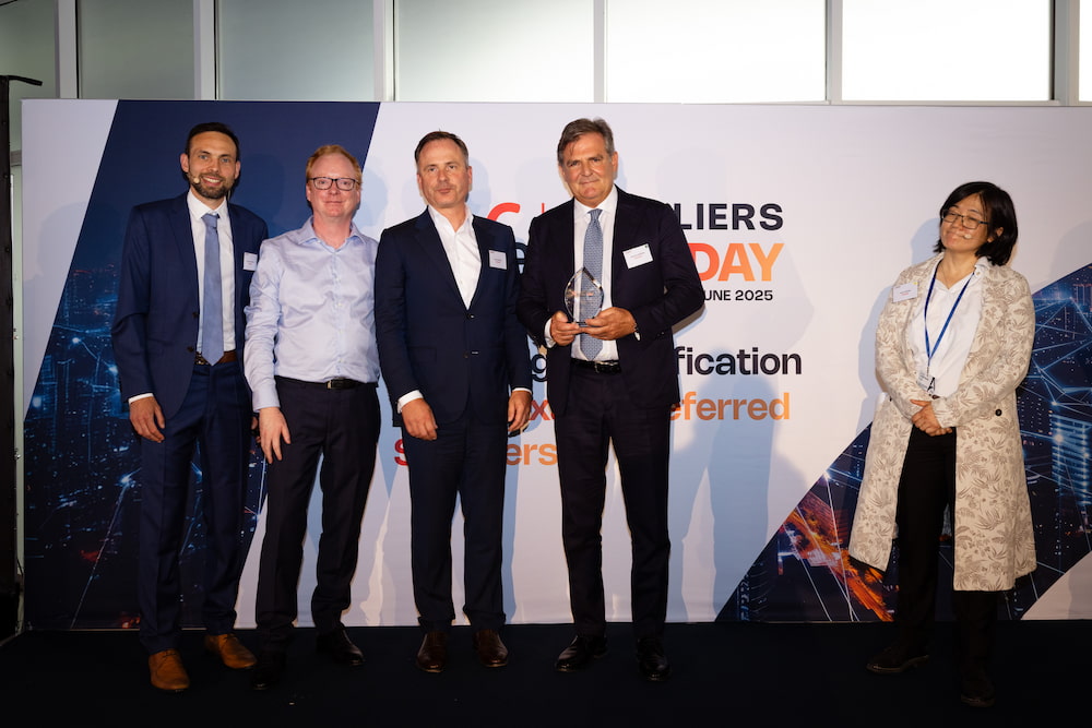 Group of professionals at Supplier's Day ceremony holding an award, colorful background with modern graphics